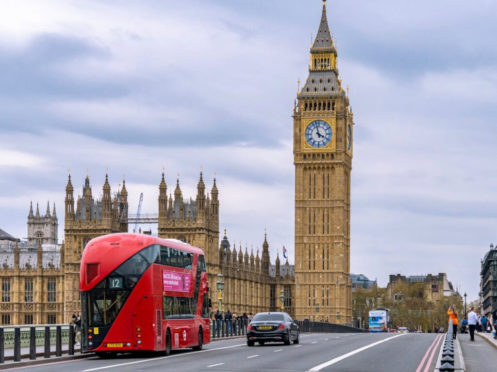 A red double-decker bus passing Big Ben.